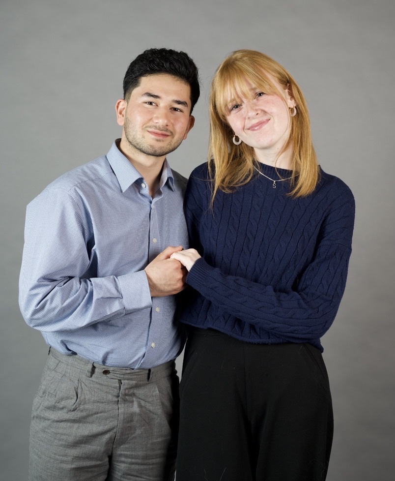 Shafi und Rika, die Gründer von ShäRi, Hand in Hand vor grauem Hintergrund
